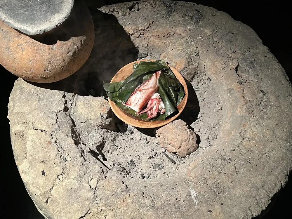 SAIMEの灰の上に置かれた土器と葉に包んだ食材
